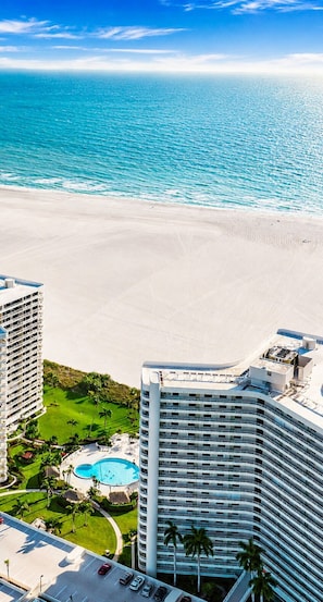 Ein Hochhaus-Hotel mit Pool, Strandblick und Parkplatz.