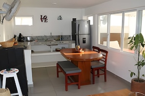 A modern kitchen with a dining area, a refrigerator, and a large window. - Amarilla (San Pedro Pochutla)