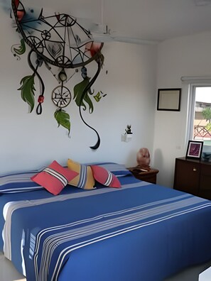 A bedroom with a bed, a wall hanging, a nightstand, and a window. - Amarilla (San Pedro Pochutla)