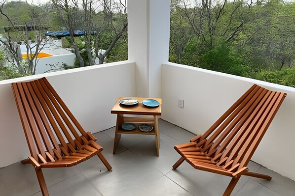 A balcony with two wooden chairs and a small table with plates. - Amarilla Playa Salchi Valentina (San Pedro Pochutla)