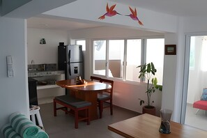 A modern kitchen with a dining area, a refrigerator, a window, and a potted plant. - Amarilla Playa Salchi Valentina (San Pedro Pochutla)
