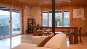 Une pièce spacieuse avec un plafond en bois, de grandes fenêtres, un coin repas et une cheminée.