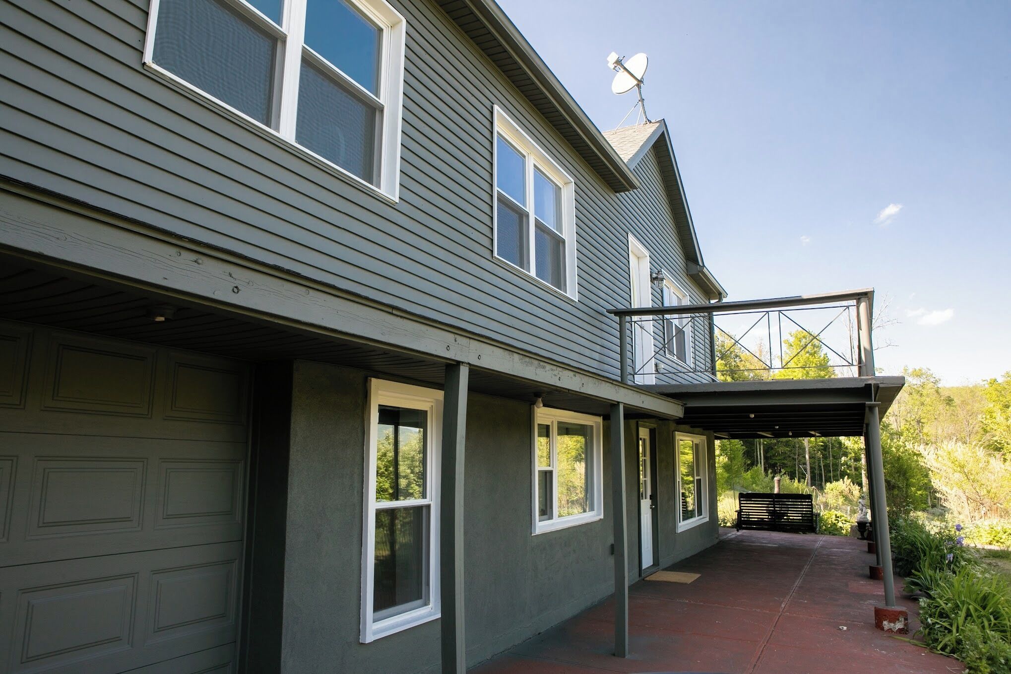 Ein zweistöckiges Haus mit überdachter Veranda, Satellitenschüssel und Garage.