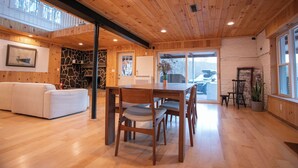 Un intérieur en bois comprenant une table à manger, des chaises, un canapé et une cheminée en pierre.
