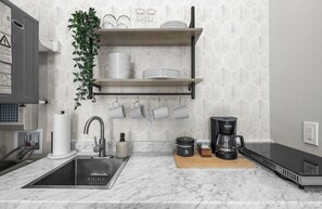 Eine Küche mit Spüle, Kaffeemaschine und einer Anrichte mit Geschirr.