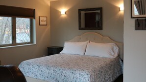 Une chambre à coucher comprenant un lit, une table de chevet, une fenêtre et des luminaires fixés au mur.