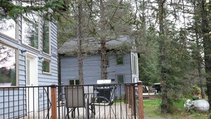 Une maison avec une terrasse, un barbecue et une chaise.