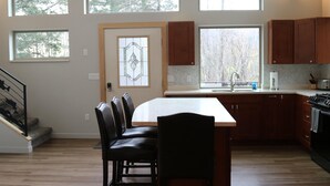 A kitchen with a central island, wooden cabinets, and a view through the windows.
