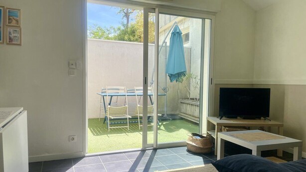 Een woonkamer met een televisie, bank en een schuifdeur die uitkomt op een terras.
