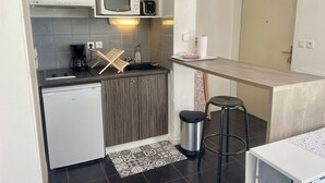 Een kleine keuken met een magnetron, koffiezetapparaat en een koelkast.