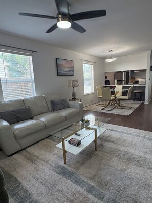 A living room with a sofa, coffee table, and a ceiling fan.