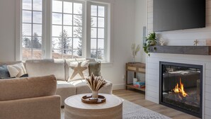Una sala de estar con chimenea, un sofá, una mesa de centro y un televisor montado en la pared.