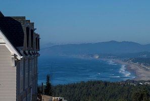 Une vue côtière avec un bâtiment, l’océan et des montagnes au loin.