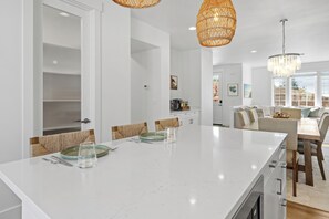 A spacious kitchen with a large island, white cabinetry, and a dining area with a table and chairs. - Brand new townhome in Depoe Bay!  Gorgeous views and neighborhood! (Depoe Bay)