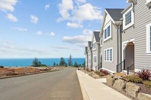 A residential street with houses, a clear sky, and the ocean in the background. - Brand new townhome in Depoe Bay!  Gorgeous views and neighborhood! (Depoe Bay)