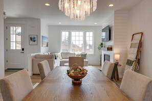 Ein Esszimmer mit Holztisch, Stühlen, einer Chandelierleuchtre und Blick ins Freie.