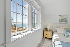 A bedroom with a large window, a bed, a bedside table, and a painting on the wall. - Brand new townhome in Depoe Bay!  Gorgeous views and neighborhood! (Depoe Bay)