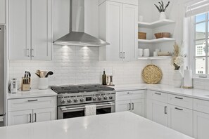 A modern kitchen with white cabinetry, a stainless steel range hood, and a central island. - Brand new townhome in Depoe Bay!  Gorgeous views and neighborhood! (Depoe Bay)