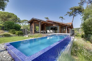 Ein modernes Haus mit Swimmingpool, Holzfassade und Terrassenbereich.
