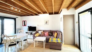 Un soggiorno con soffitto in legno, un divano, un tavolino da caffè, una televisione e una porta.