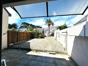A covered outdoor area with a gravel path leading to a house, surrounded by a wooden fence and vegetation. - House 3 bedrooms 4 people in Guidel, only 400 m from the beach, enclosed garden, wifi (GUIDEL)