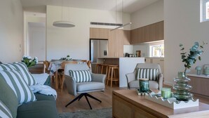 Een moderne woonkamer met een bank, fauteuils, een salontafel, en een eethoek met een tafel en stoelen.