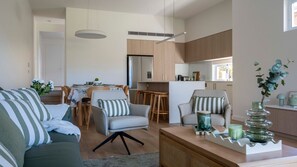 Ein modernes Wohnzimmer mit Sofa, Sesseln, einem Couchtisch und einem Essbereich mit Tisch und Stühlen.