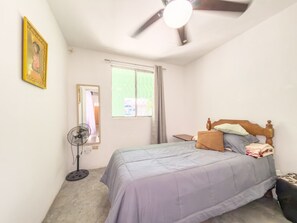 A bedroom with a bed, a ceiling fan, a standing fan, a window with curtains, and a framed picture on the wall. - Casa equipada 3 recs. cerca aeropuerto (Ciudad Apodaca)