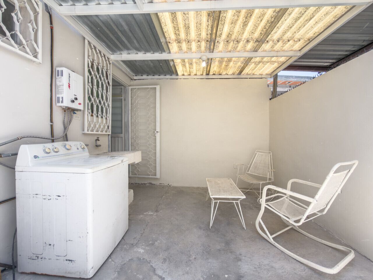 A laundry area with a washing machine, a small table, and a rocking chair.