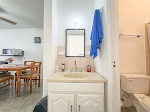 Un baño con lavabo, espejo e inodoro.