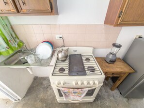 Une cuisine équipée d’une cuisinière, d’un évier et d’un mixeur, le tout installé sur une petite table en bois.