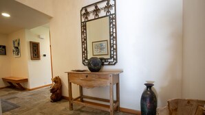 Una consola de madera con un jarrón y un espejo encima.