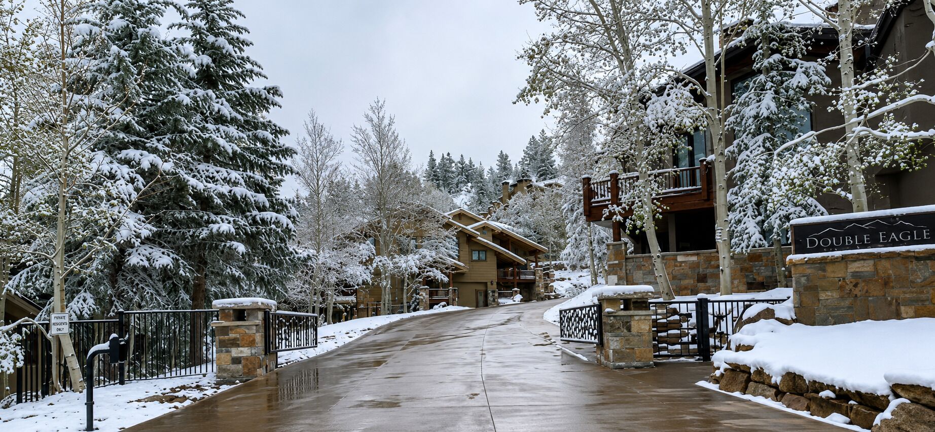 A snow-covered entrance to a lodge with a stone wall and a sign reading 'DOUBLE EAGLE.'