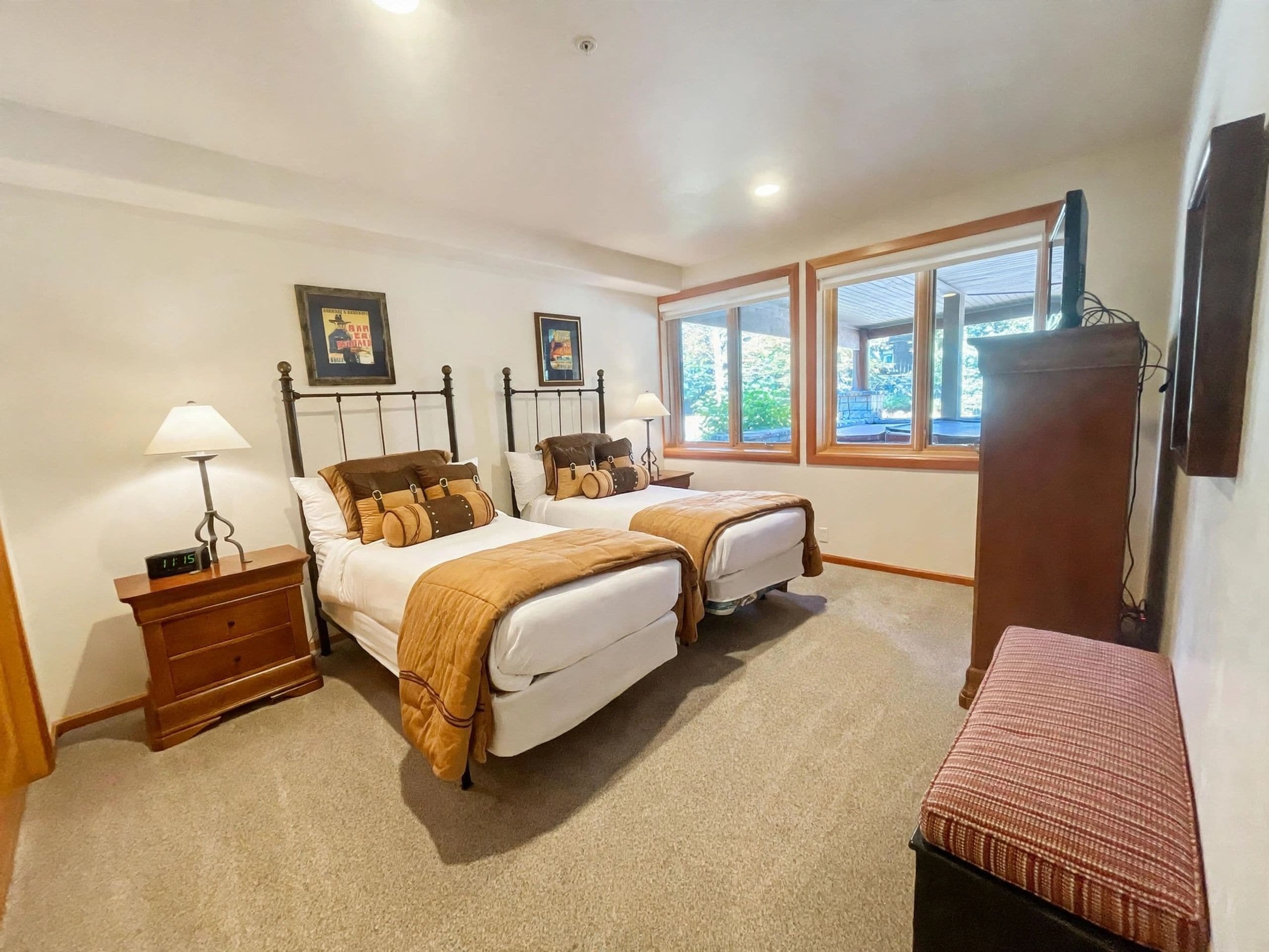 Une chambre d’hôtel avec deux lits, une table de chevet avec une lampe, un bureau avec un ordinateur et une fenêtre donnant sur l’extérieur.