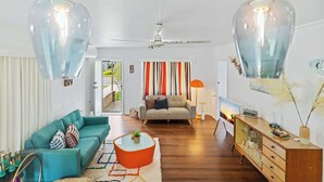 A living room with a sofa, coffee table, and a cabinet. - The Tides - 70s Seaside Bungalow (Port Douglas)