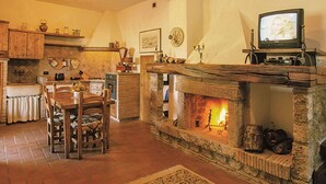 A cozy living room with a stone fireplace, wooden furniture, and a television. - Wonderful private villa for 8 people with WIFI, A/C, private pool, TV and pets allowed (Roccastrada)