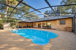 An indoor swimming pool with a glass ceiling, surrounded by a patio area with seating and a brick wall. - DeLand Spring House — Pool, 3/3.5, Near Blue Spring Manatees (DeLand)
