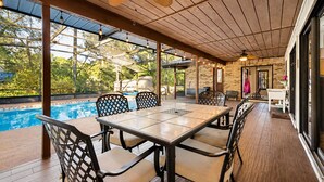 A covered outdoor area with a pool, wooden deck, and a table with chairs. - DeLand Spring House — Pool, 3/3.5, Near Blue Spring Manatees (DeLand)