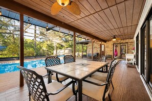 A covered outdoor area with a pool, wooden deck, and a table with chairs. - DeLand Spring House — Pool, 3/3.5, Near Blue Spring Manatees (DeLand)