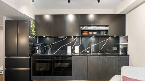 Una cocina moderna con armarios oscuros, encimera negra y horno integrado.