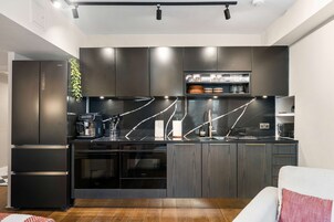 Una cocina moderna con armarios oscuros, encimera negra y horno integrado.