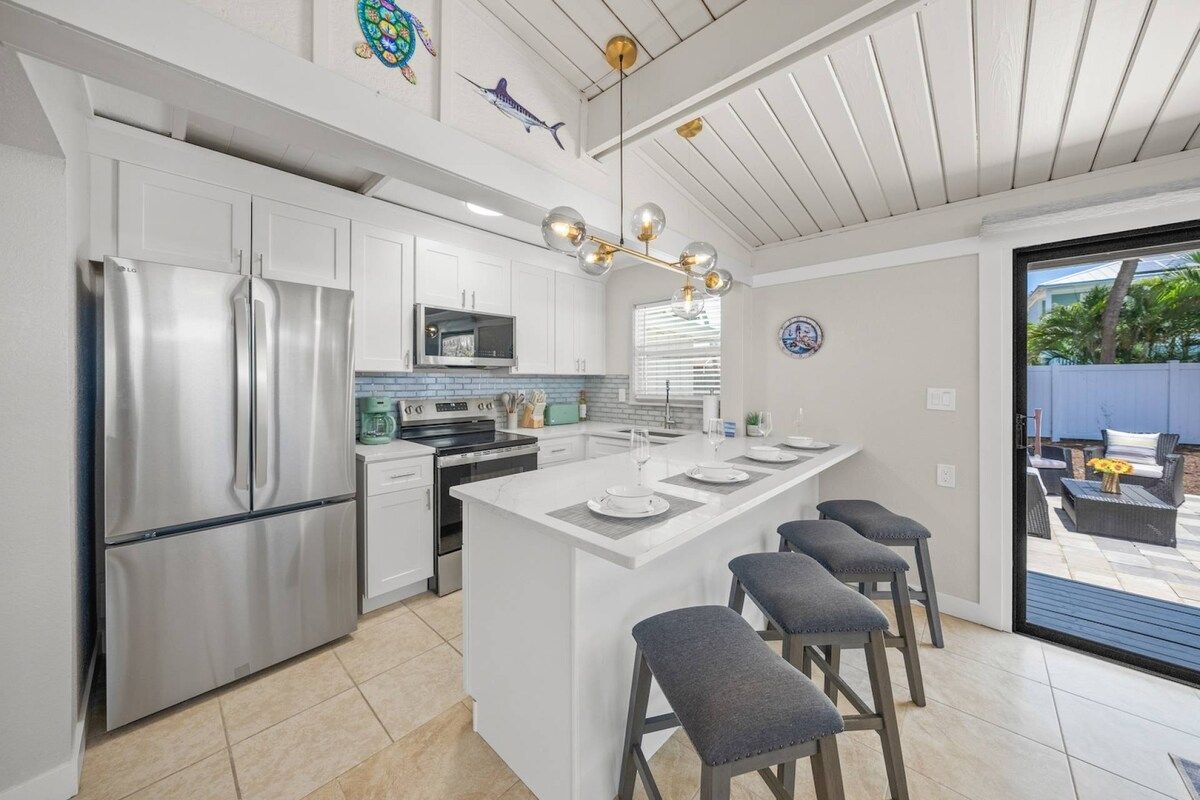 A modern kitchen with a central island, stainless steel appliances, and a view to the outdoor patio.