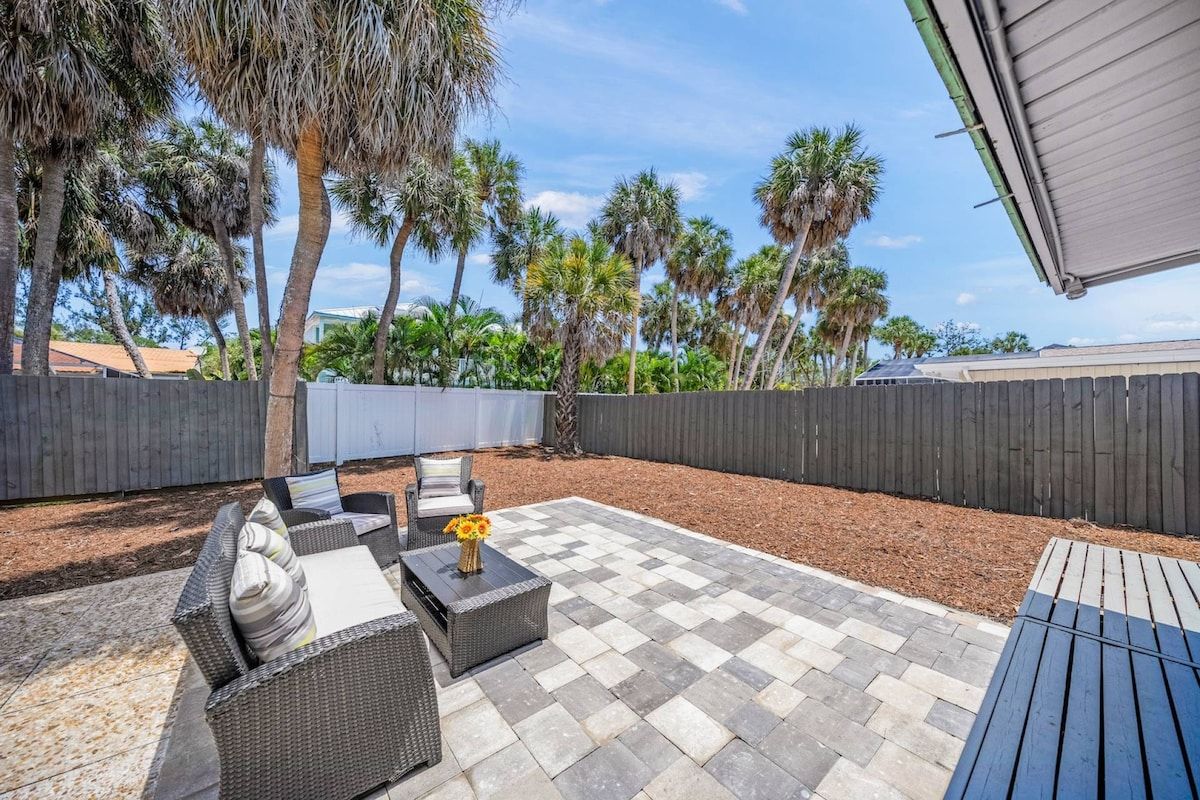 An outdoor patio with wicker furniture, a checkered floor, and a wooden fence.