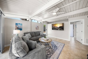 A spacious living area with a gray sofa, a round coffee table, and artwork on the walls. - Salt & Sand Beach Shack: Modernized Siesta Duplex (Siesta Key)