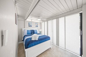 Ein Schlafzimmer mit Bett, Deckenventilator und Fenster mit Jalousien.