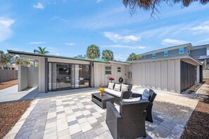 Un espace patio aménagé avec du mobilier d’extérieur, un coin salon abrité et une vue sur le jardin arrière.