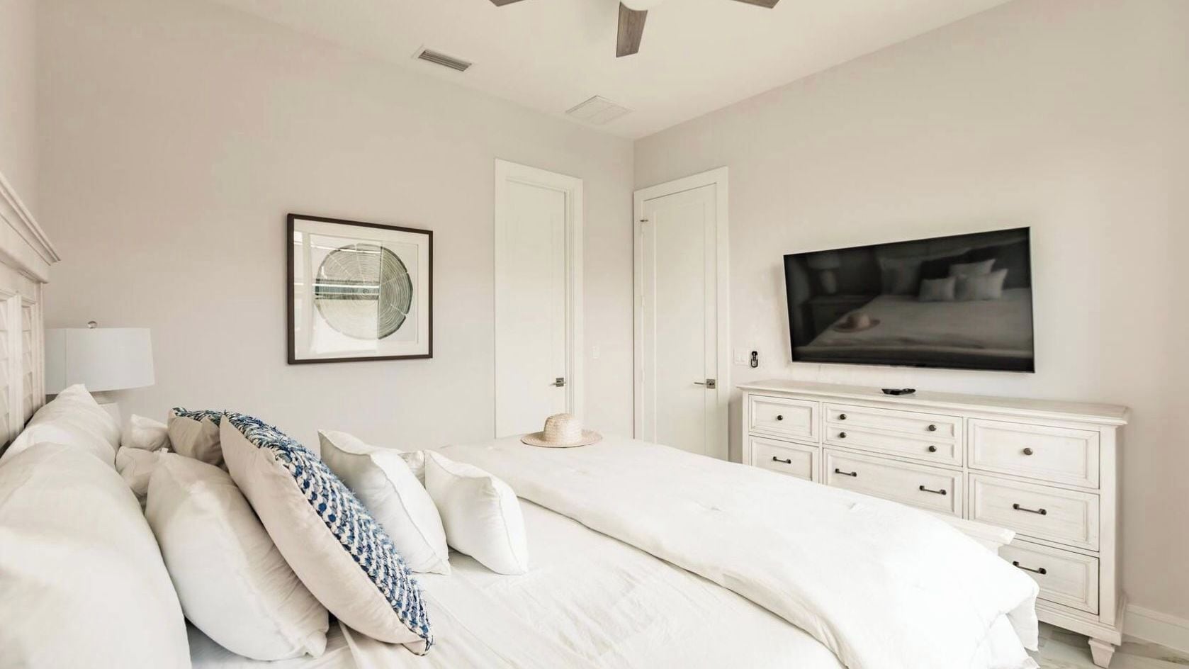 Une chambre à coucher avec un lit, une commode, un téléviseur et un tableau encadré au mur.