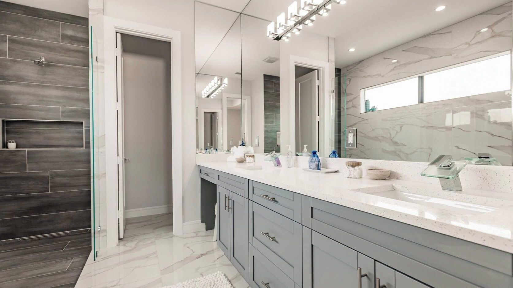 Une salle de bain moderne dotée d’un grand miroir, de deux vasques et d’une cabine de douche en verre.