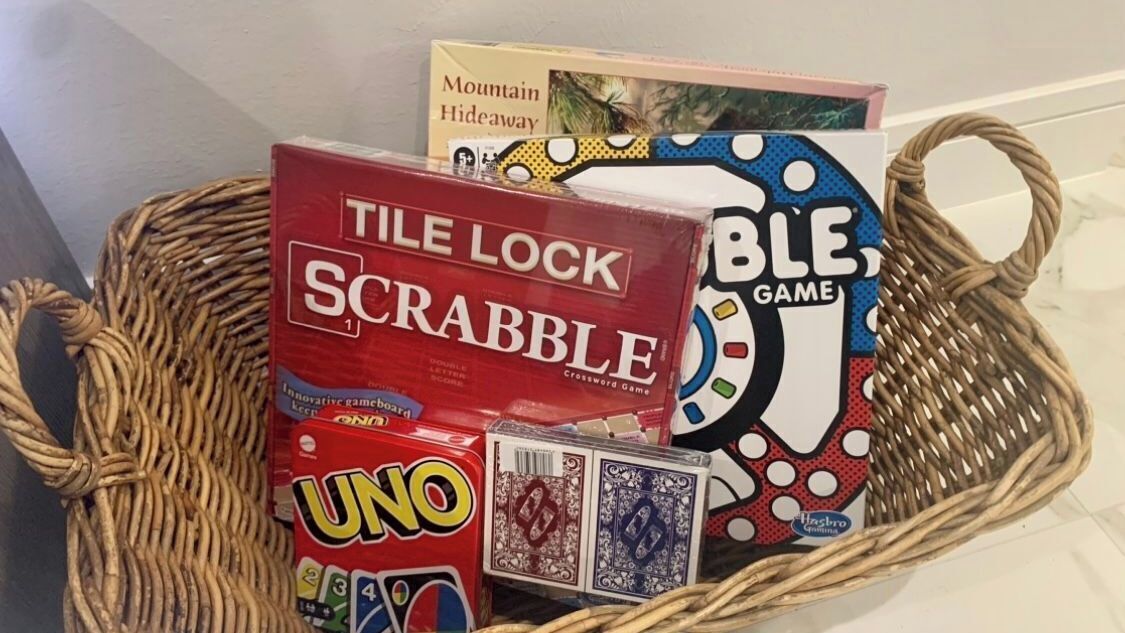 A basket containing Tile Lock Scrabble, UNO, and a board game.