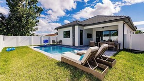 A modern house with a swimming pool, outdoor seating, and a fenced backyard. - Brisa del Mar by Avantstay 4BR Coastal-modern Retreat + Private Pool + Outdoor Dining Walk to the Gulf + Mercato Minutes Away (Naples)